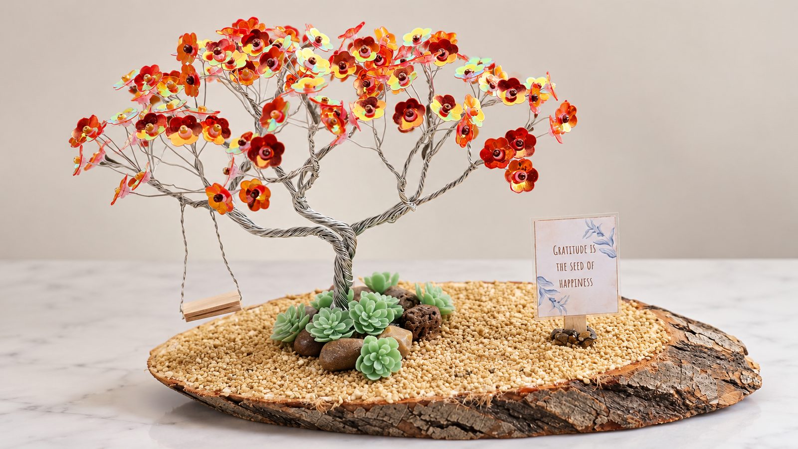 Árbol de otoño de alambre con lentejuelas rojas y naranjas, columpio y tarjeta sobre una rodaja de madera